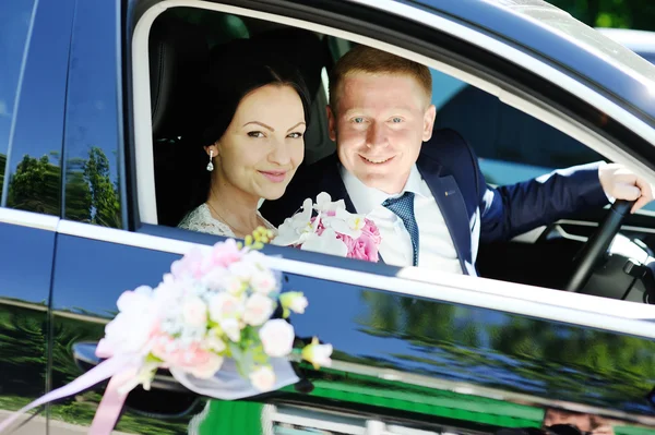 The bride and groom in a wedding car — Stock Photo, Image