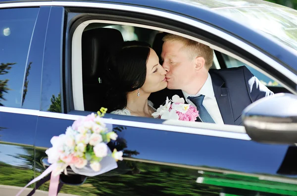 Bride and groom kissing in wedding car — Stock Photo, Image