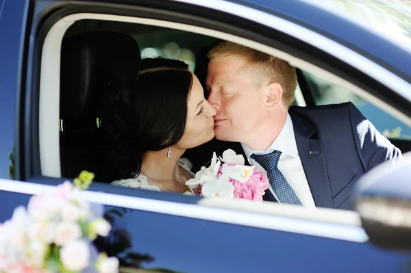 Bride and groom kissing in wedding car — Stock Photo, Image