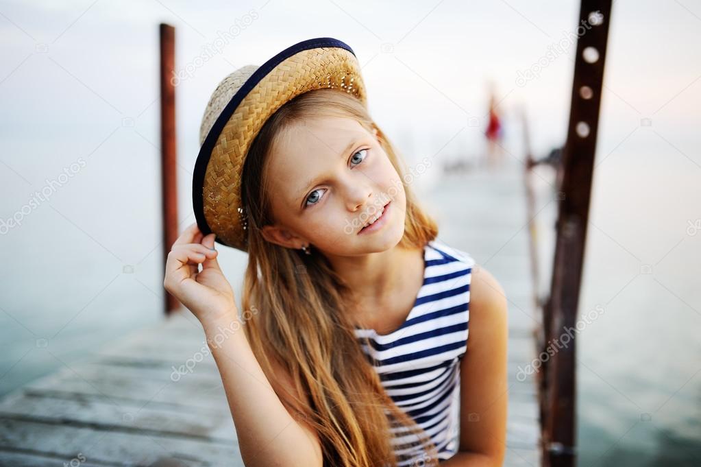 Girl in striped vest and a straw hat against the sea