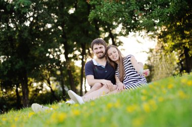 gün batımında çimlerde oturan genç Çift