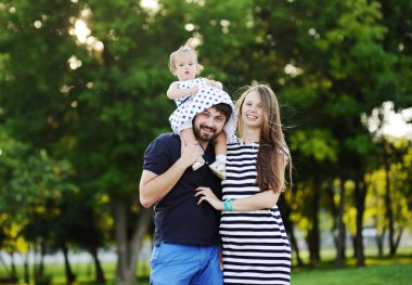 Yeşil trees.little kız giyiyor genç aile arka plan üzerinde 