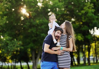 Yeşil trees.little kız giyiyor genç aile arka plan üzerinde 