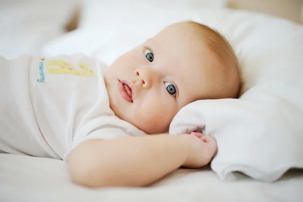Retrato de um bebé. Menino deitado na cama e olhando para o — Fotografia de Stock
