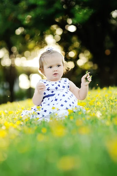 Kleines Mädchen im weißen Kleid sitzt auf dem Gras — Stockfoto