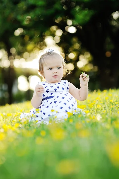 Kleines Mädchen im weißen Kleid sitzt auf dem Gras — Stockfoto