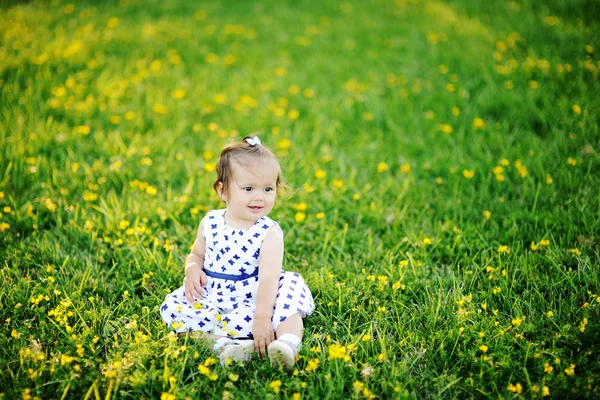 Маленькая девочка в белом платье сидит на траве — стоковое фото