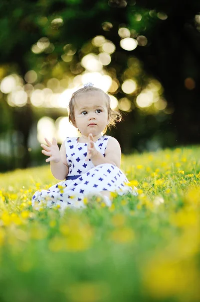 Kleines Mädchen im weißen Kleid sitzt auf dem Gras — Stockfoto