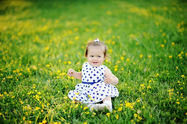 Маленькая девочка в белом платье сидит на траве — стоковое фото