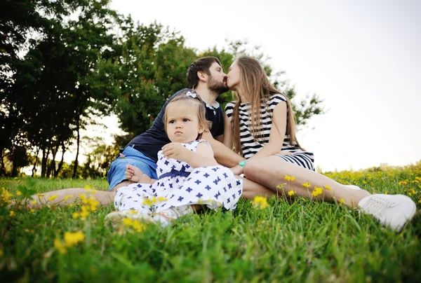 Familia joven relajándose en el parque en la hierba. niña jugar — Foto de Stock