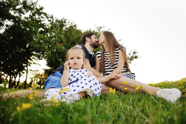 Jovem família relaxando no parque na grama. menina jogar — Fotografia de Stock