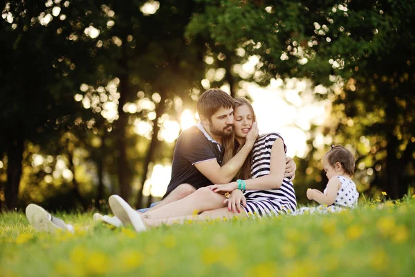 Genç aile rahatlatıcı parkta çim. — Stok fotoğraf