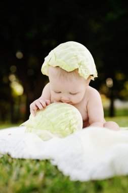 lahana ile kız bebek. Lahana bir çocuğun kafasına bırakır. Çocuk rahatlatıcı bir parkta çim.