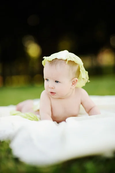 Bambina col cavolo. Foglie di cavolo sulla testa di un bambino . — Foto Stock