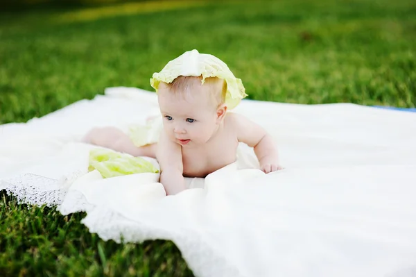 Baby girl with cabbage. Cabbage leaves on the head of a child. Child relaxing in a park on the grass. — Stock Photo, Image