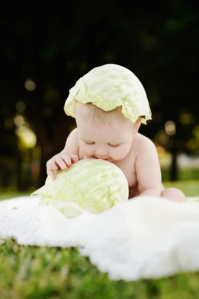 Petite fille au chou. Les feuilles de chou sur la tête d'un enfant. Enfant relaxant dans un parc sur l'herbe . — Photo