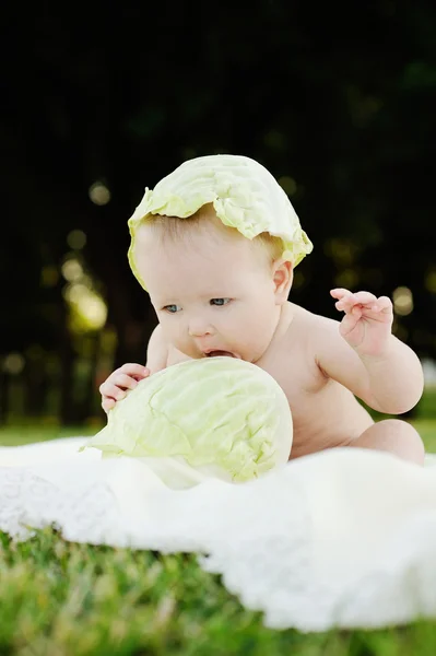 Petite fille au chou. Les feuilles de chou sur la tête d'un enfant. Enfant relaxant dans un parc sur l'herbe . — Photo