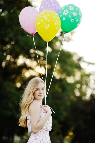 Young girl with colored balloons on a background of trees and the sunset — Stock Photo, Image