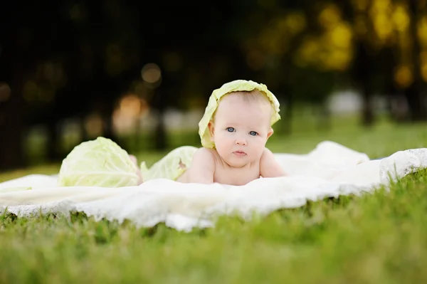 Bayi perempuan dengan kubis. Kubis daun di kepala seorang anak. C — Stok Foto