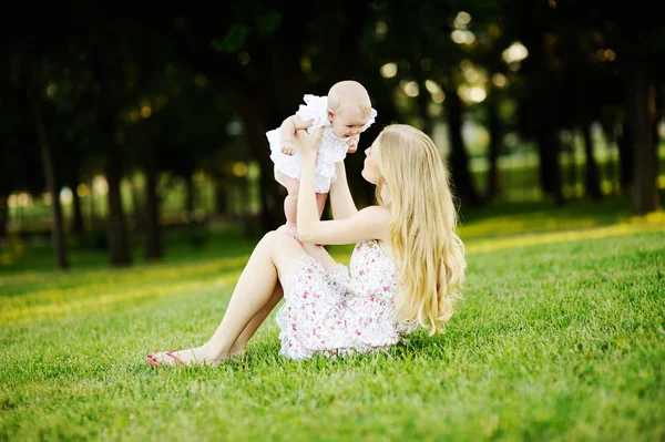 Ung mamma och lilla dotter avkopplande i parken på gra — Stockfoto