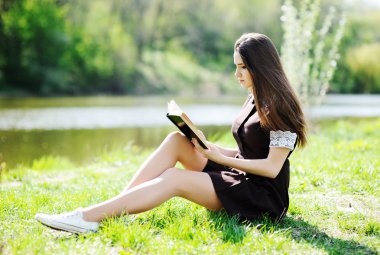 Bir kitap rahatlatıcı parkta çim ile kız öğrenci