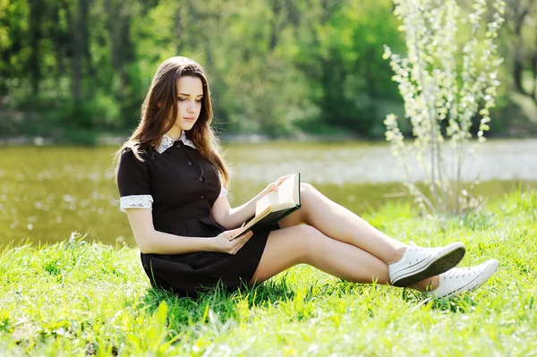 Gadis sekolah dengan buku santai di taman di rumput. — Stok Foto