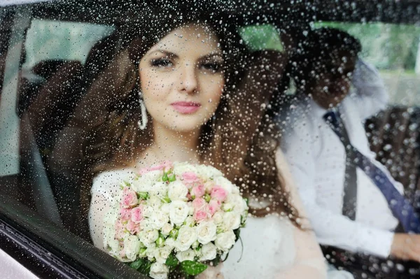 濡れたガラスの背後にある少女の肖像画。花嫁が結婚式の車 — ストック写真