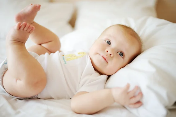 Portrait de bébé aux yeux bleus. Un enfant reposant sur un lit — Photo