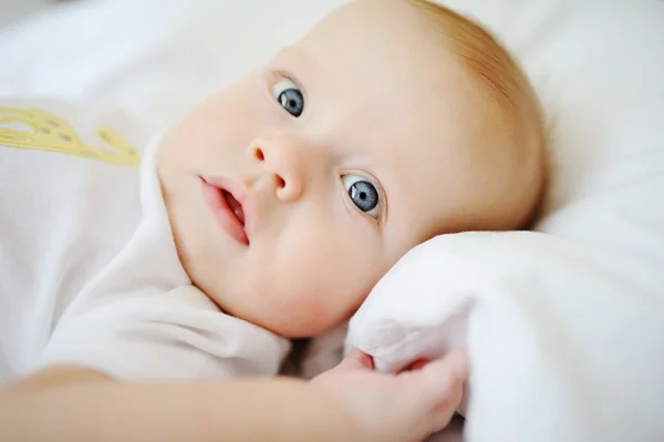Retrato de bebê com olhos azuis. Uma criança descansando em uma cama — Fotografia de Stock