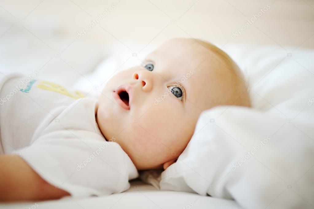 portrait of baby with blue eyes. A child resting on a bed