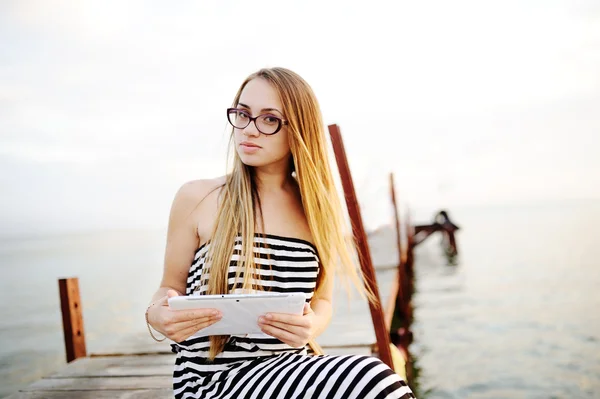 Chica con gafas en un vestido a rayas con una tableta de ordenador en h — Foto de Stock