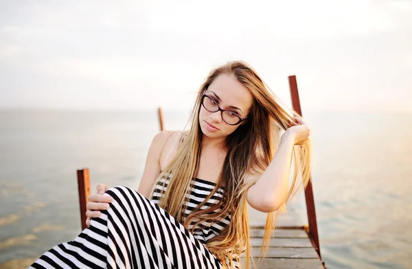 Deniz bir arka plan üzerinde çizgili bir elbise içinde gözlük ile kız — Stok fotoğraf