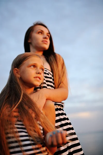 Duas meninas em vestido listrado ao pôr do sol — Fotografia de Stock