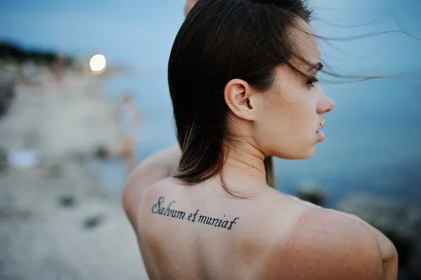 Девушка с татуировкой на спине на фоне моря — стоковое фото