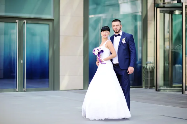 La mariée et le marié sur le fond du bâtiment en verre — Photo