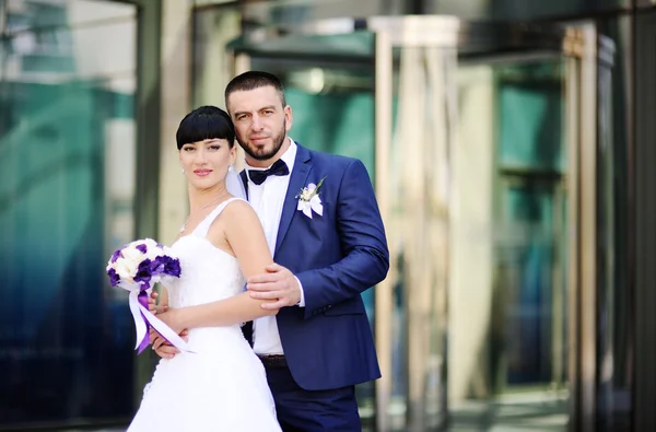 La mariée et le marié sur le fond du bâtiment en verre — Photo