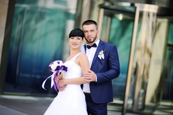 La mariée et le marié sur le fond du bâtiment en verre — Photo