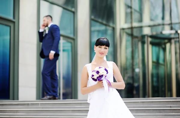 La mariée et le marié sur le fond du bâtiment en verre — Photo