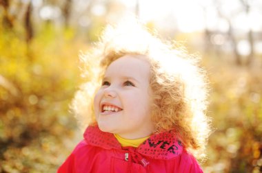 sonbahar arka plan üzerinde kırmızı kıvırcık saçlı çocuk bırakır