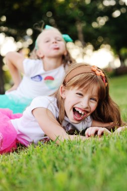 çim zemin üzerine iki küçük kız yüz buruşturma