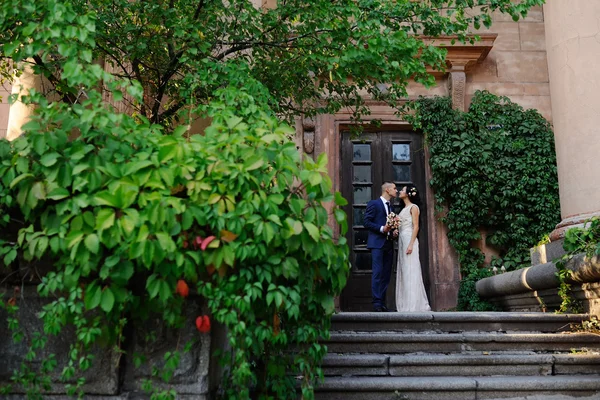 De bruid en de bruidegom met een boeket van de bruiloft op de achtergrond van — Stockfoto