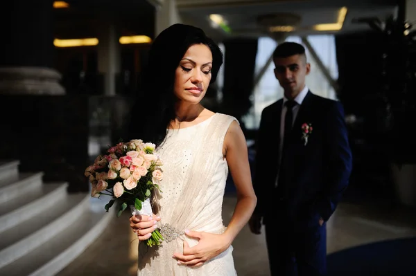 Bruid en bruidegom met een boeket van de bruiloft in de achtergrond Interio — Stockfoto