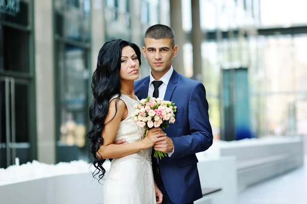 Pengantin wanita dan pengantin pria di latar belakang bangunan kaca — Stok Foto