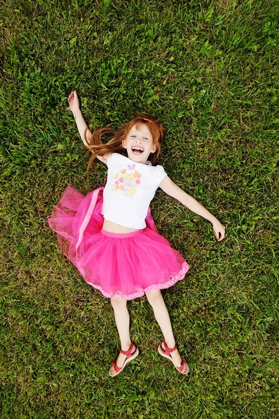 Смішна руда дівчина відпочиває на траві в парку — стокове фото