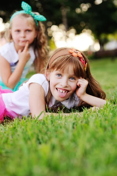 Two little girls grimace on the grass background — Stock Photo, Image