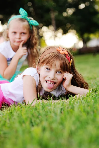 Two little girls grimace on the grass background — Stock Photo, Image