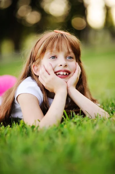 Engraçado menina ruiva relaxante na grama no parque — Fotografia de Stock