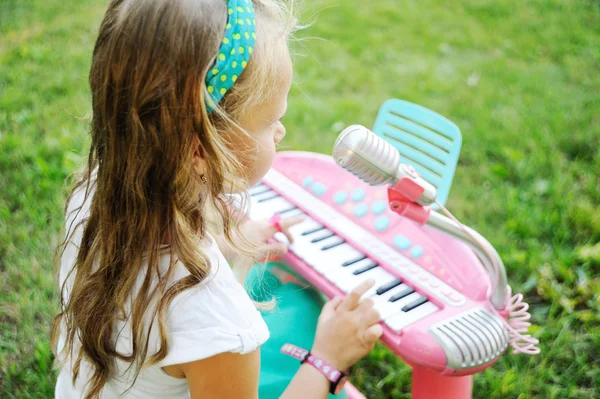 Criança menina tocando em um piano de brinquedo — Fotografia de Stock