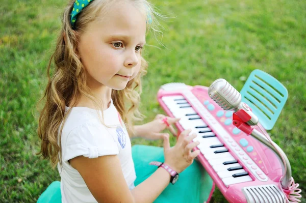 Enfant petite fille jouant sur un piano jouet — Photo