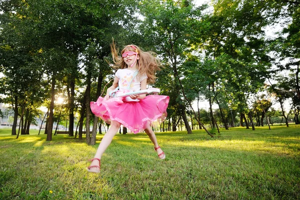 Bambina che salta con una chitarra giocattolo — Foto Stock